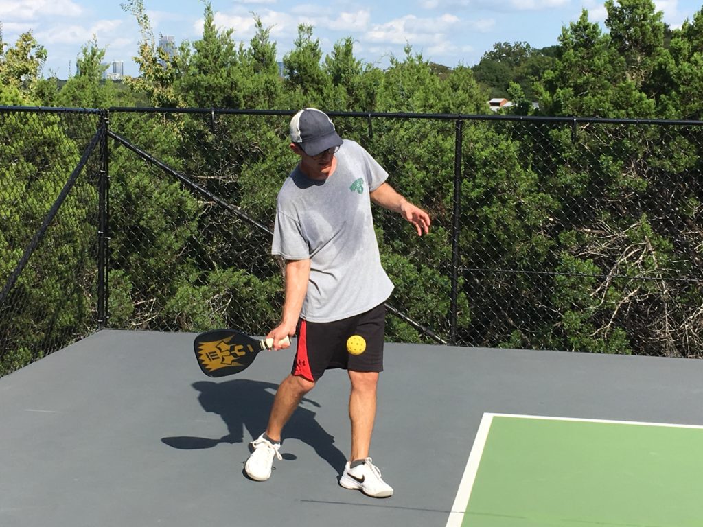 Calvin Serving the Pickleballball wearing a gray shirt