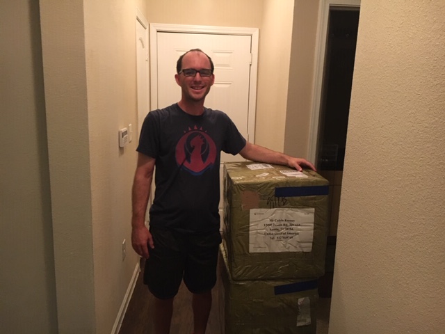 Calvin Keeney standing next to shipping boxes full of C DRIVE Pickleballs and some Paddles