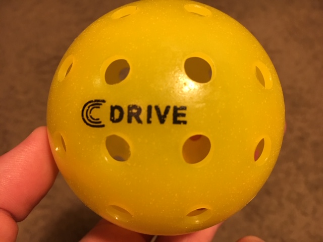 The Yellow C DRIVE Pickleball in Calvin Keeney's Hand held up close to the camera