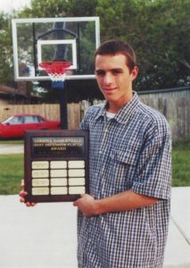 Calvin Keeney holding his "Defensive Player of the Year Award" that he won two times in High School. He is in front of his basketball goal at his home driveway