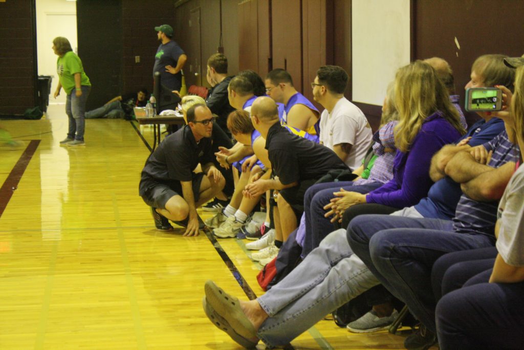 Calvin Keeney kneeling down to talk to one of his athletes on the Special Olympics Basketball Team He Coached for Down Home Ranch