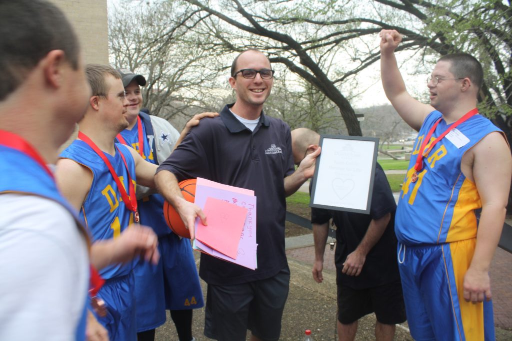 Calvin Keeney holding a "Coach of the Year" Award that his Assistant Coach Presented to Him After Special Olympics Regionals in Texas February 2018